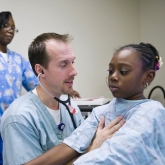 A doctor checks a young girl's heart in a hospital. A doctor checks a young girl's heart in a hospital.