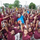 A coach surrounded by a group of kids; all have a raised fist (as a symbol of unity, solidarity, and support). thumbnail