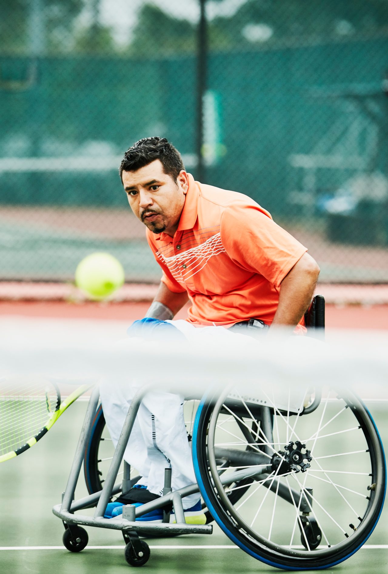 Adaptive athlete chasing down shot during wheelchair tennis match