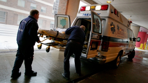 Paramedics load a gurney into an ambulance.