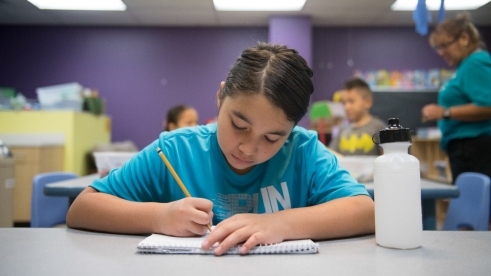 A girl writes in a notebook in class.