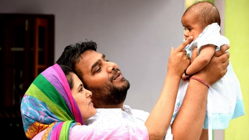 A father and mother hold their baby.