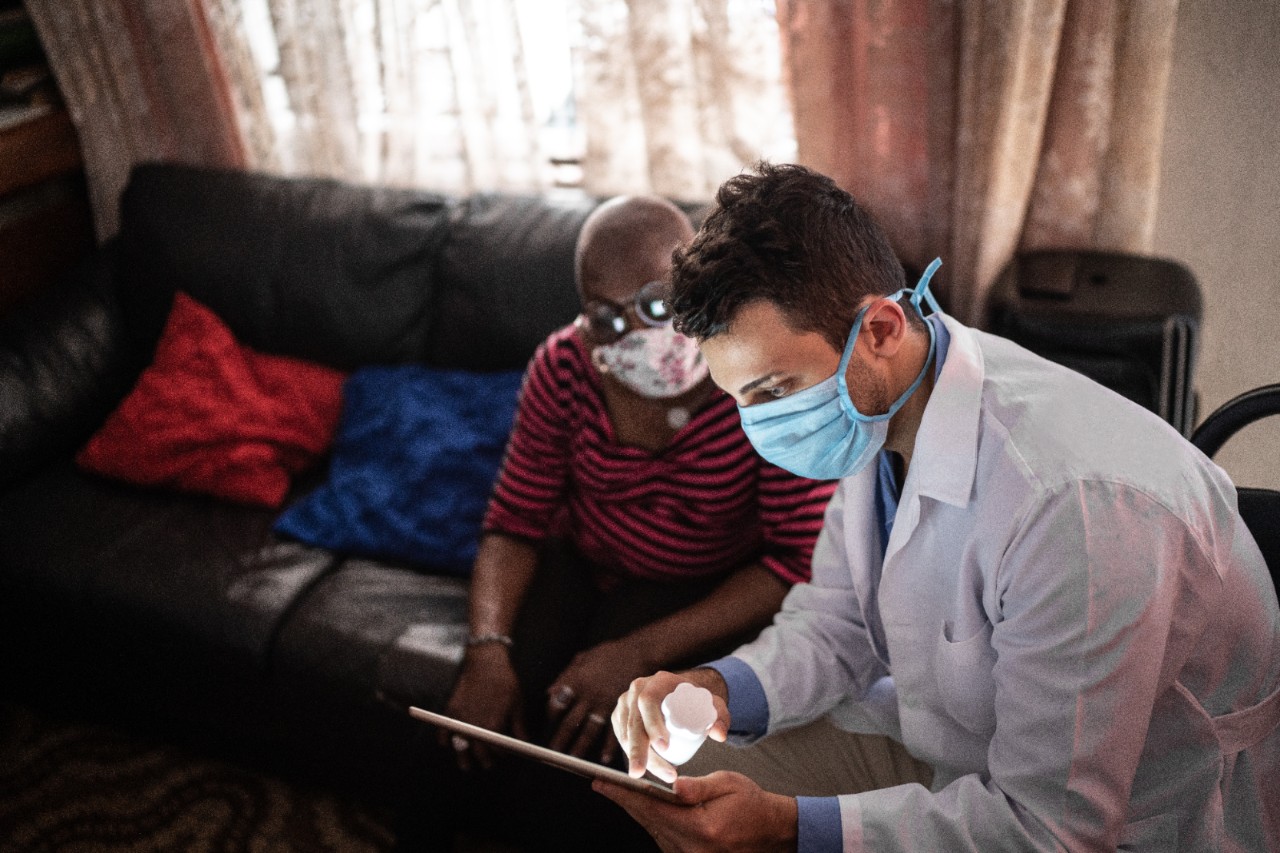 A doctor assisting a patient at home.