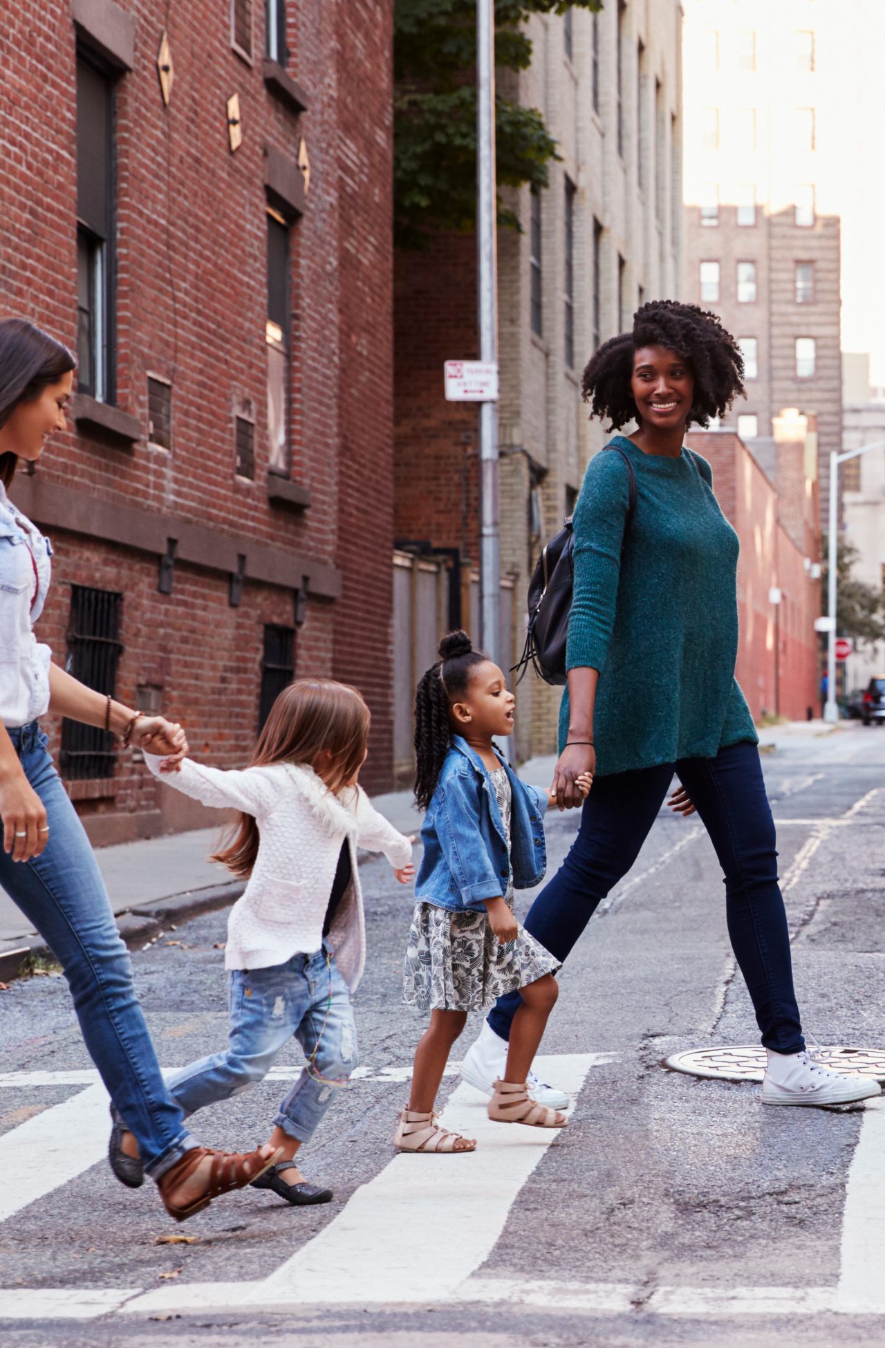 Two women and their daughters crossing a street.