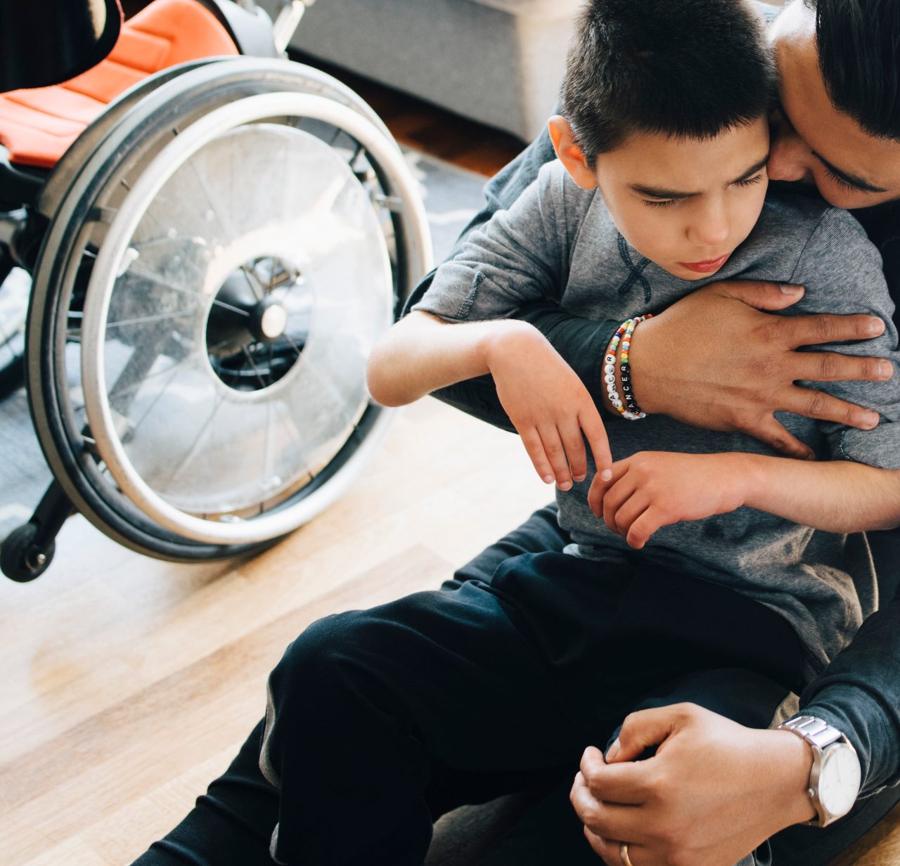 A man holds and hugs a disabled boy..