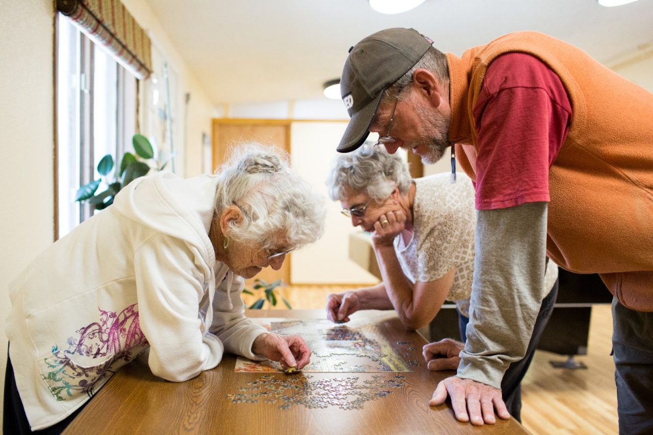 Three seniors working on a puzzle at a senior center. 