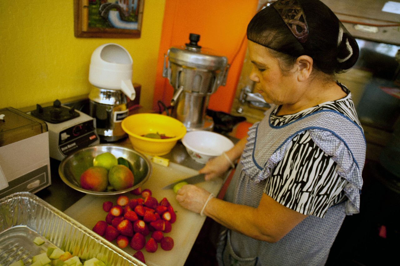 A woman preparing fruit in restaurant kitchen.