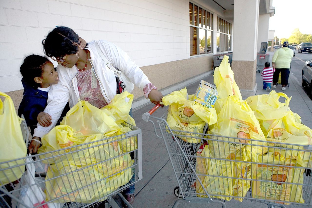 A girl and her mother push shopping carts full of grocery bags. Food Trust