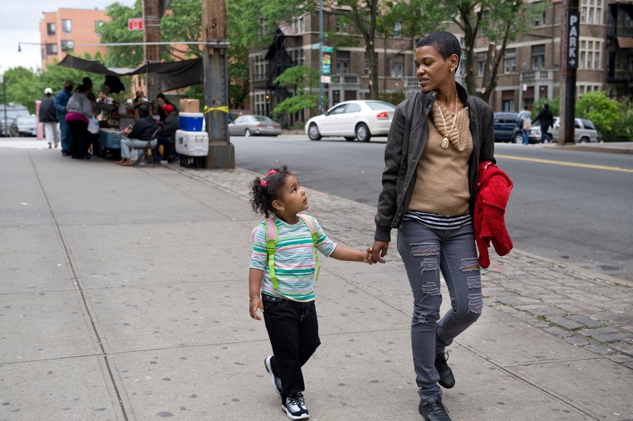 A woman walking along a city street holding a young girl's hand.