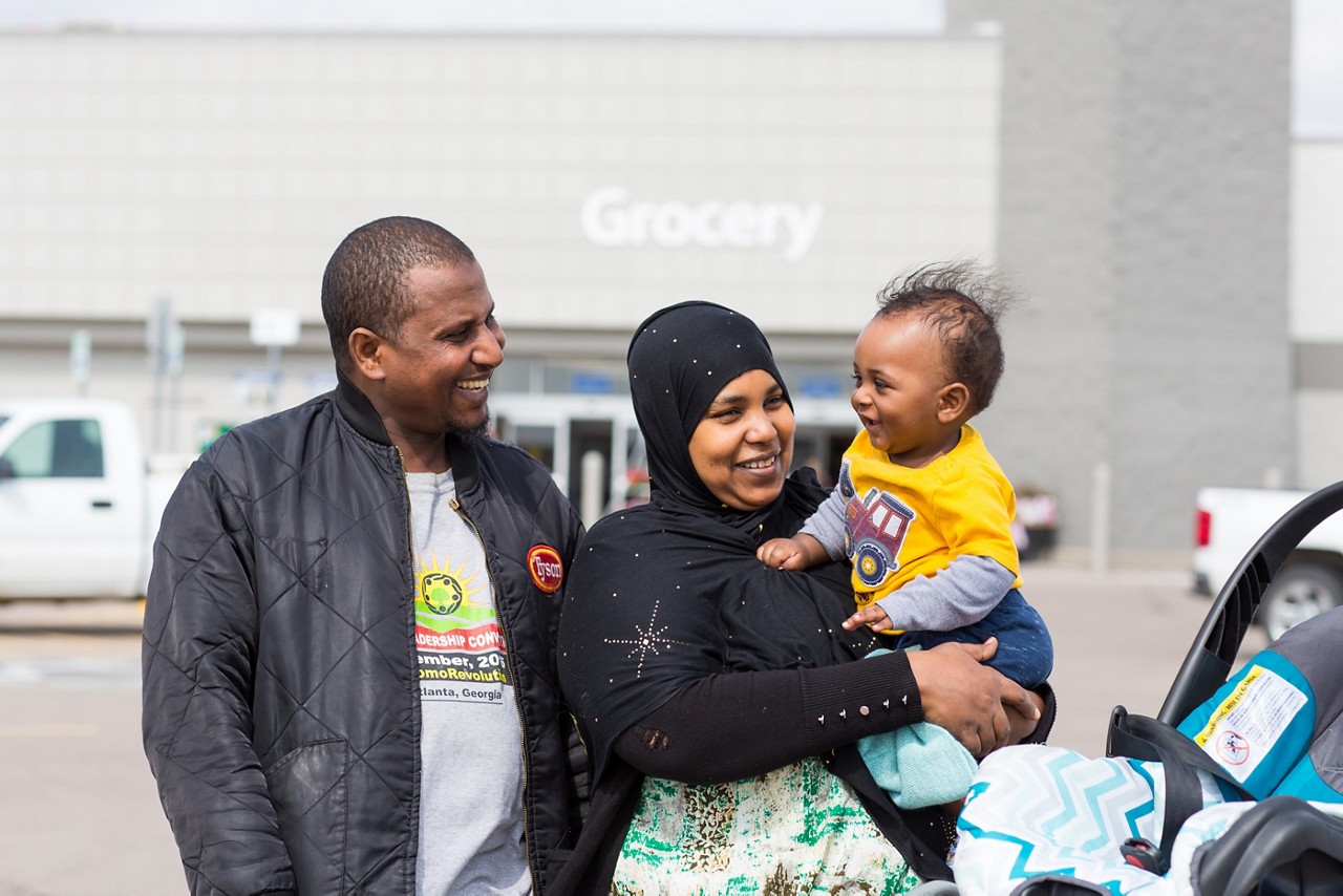 Parents  smiling while holding their toddler.