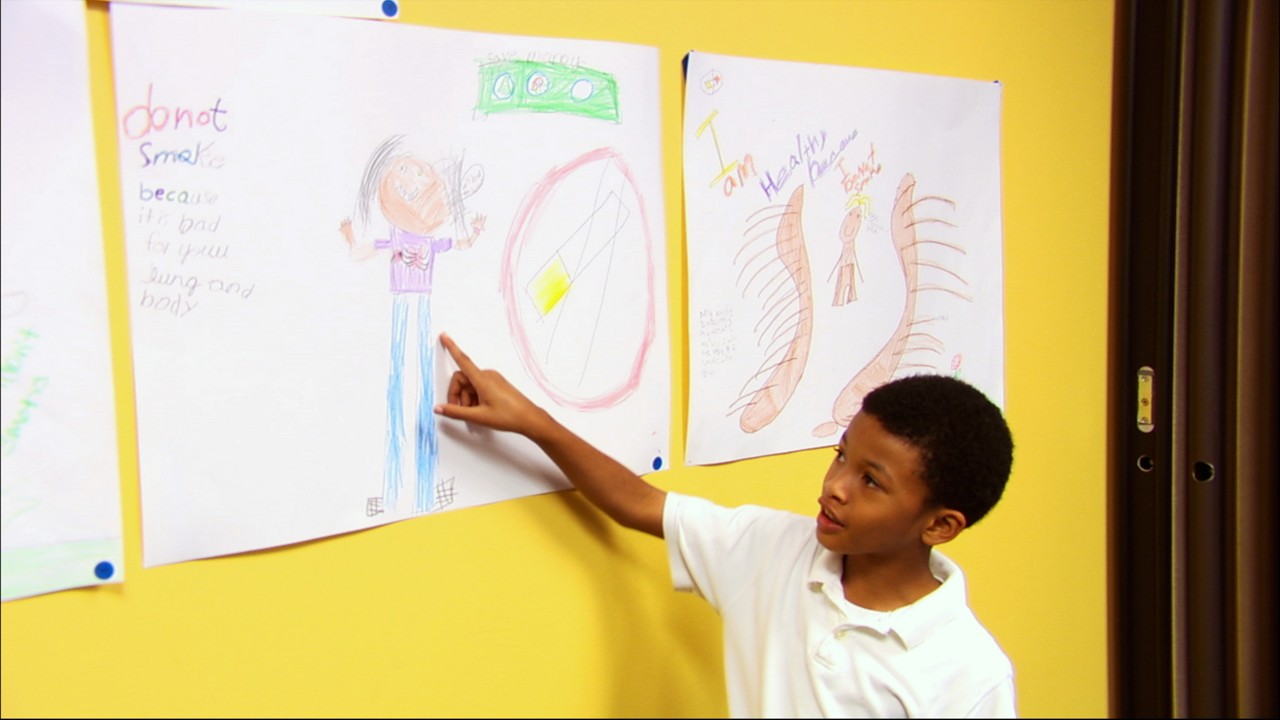 A young boy pointing to a smoking cessation poster.