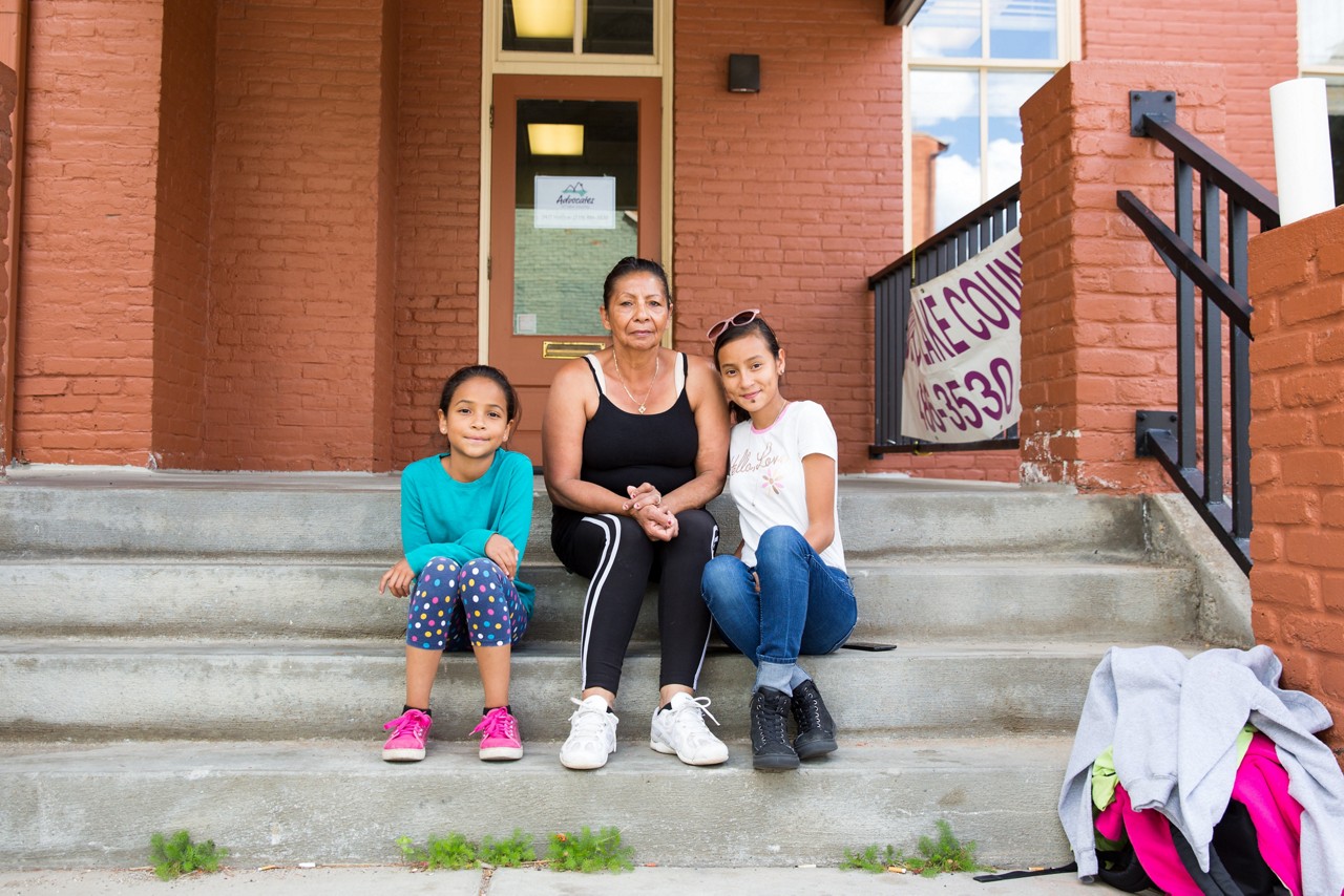 A mother and her two daughters sitting on steps.