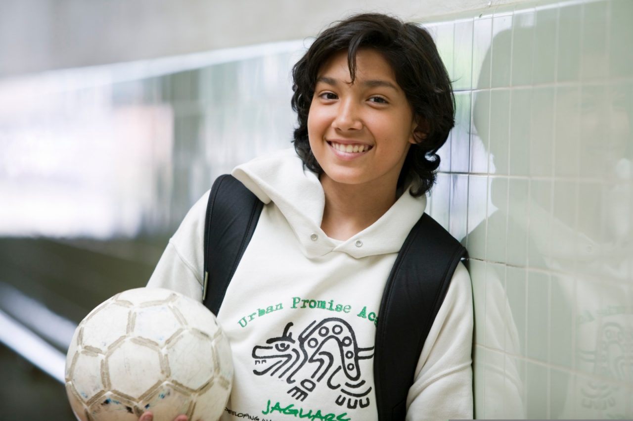 A teenage girl holding a soccer ball.