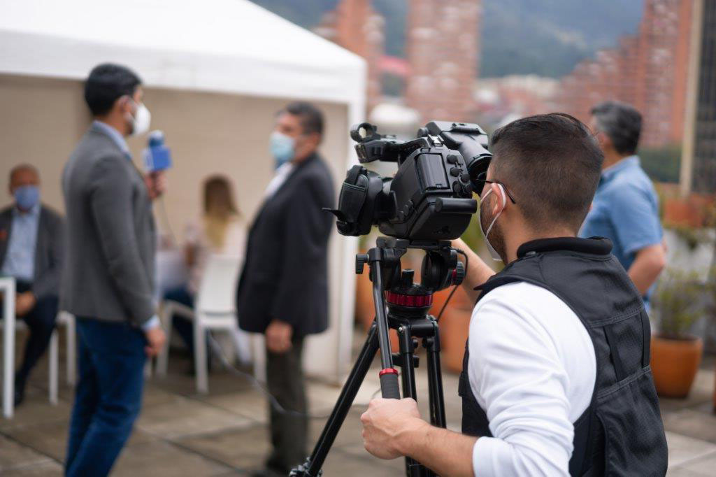 A cameraman recording the latest news from a COVID-19 vaccination stand.