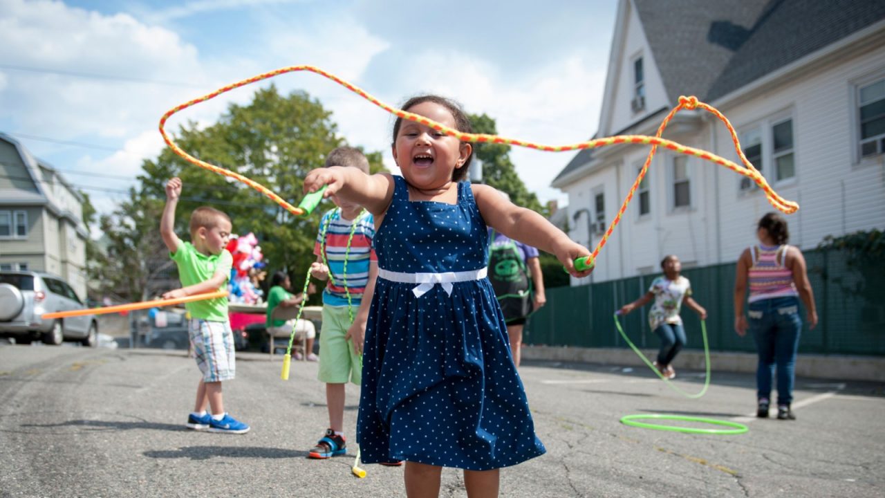 A girl in a blue dress jumping rope.