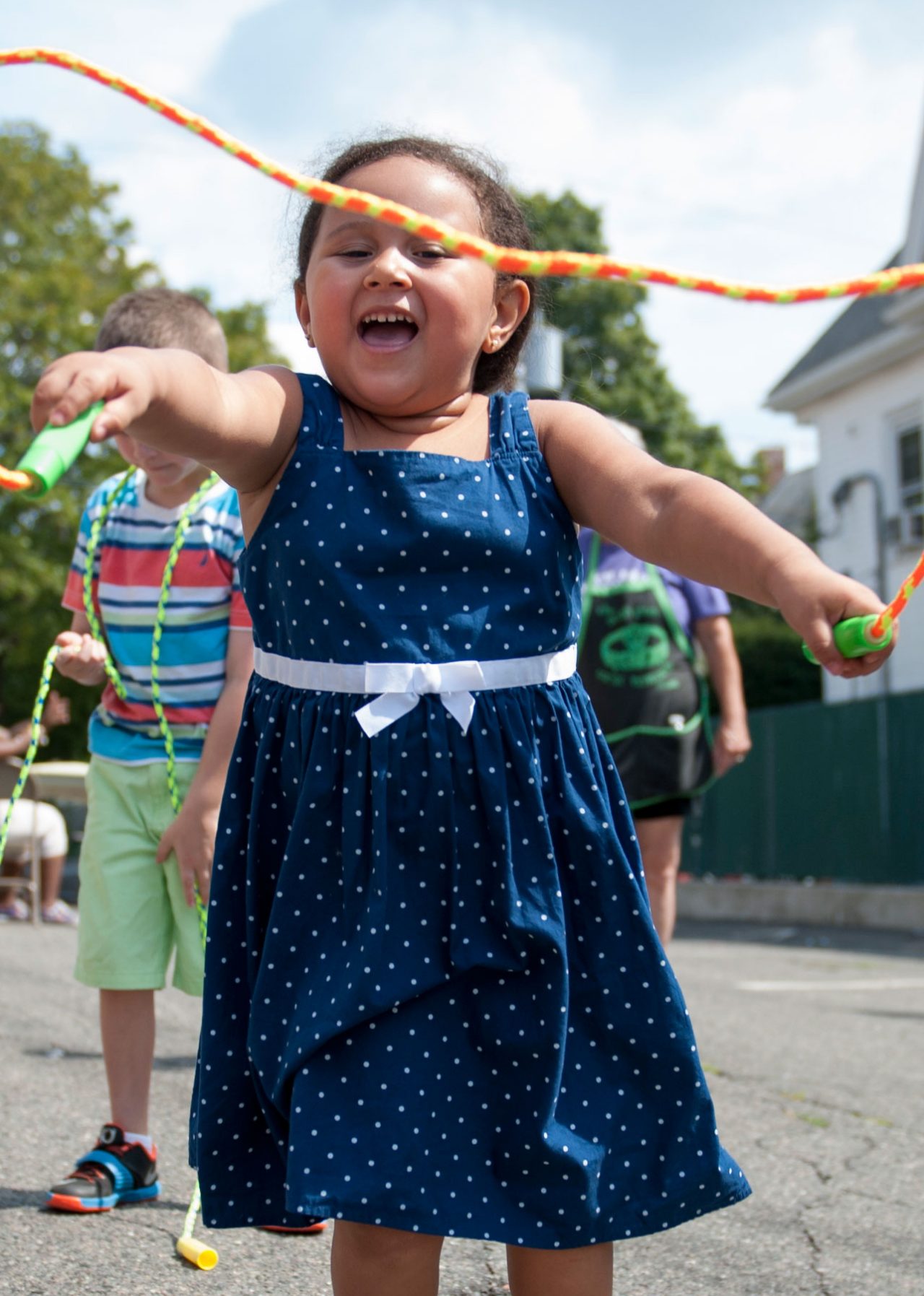 A girl in a blue dress jumping rope.