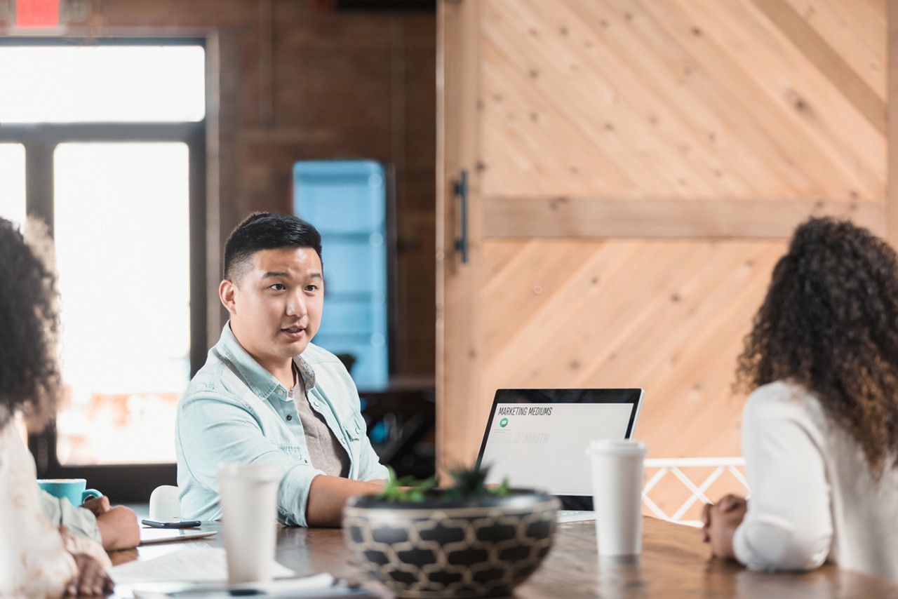 A male marketing executive discusses marketing strategy with a group of colleagues. He is using a laptop during the presentation. A male marketing executive discusses marketing strategy with a group of colleagues. He is using a laptop during the presentation.