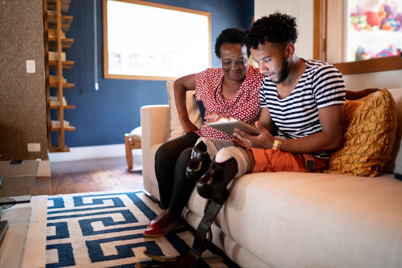 Son/Grandson using digital tablet with his mother/grandmother Son/Grandson using digital tablet with his mother/grandmother