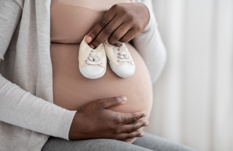 Pregnant woman holding baby shoes.