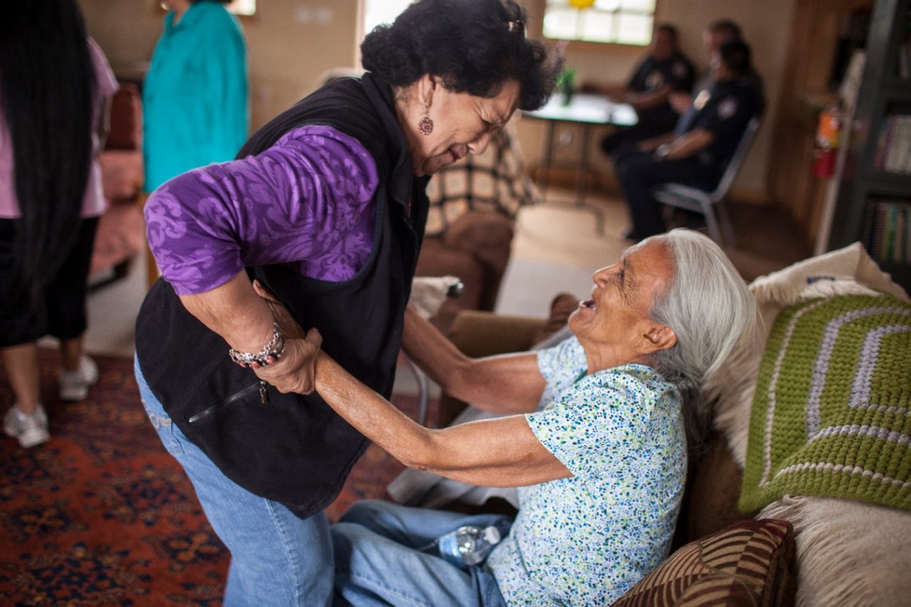 A caregiver helping an elderly woman stand.