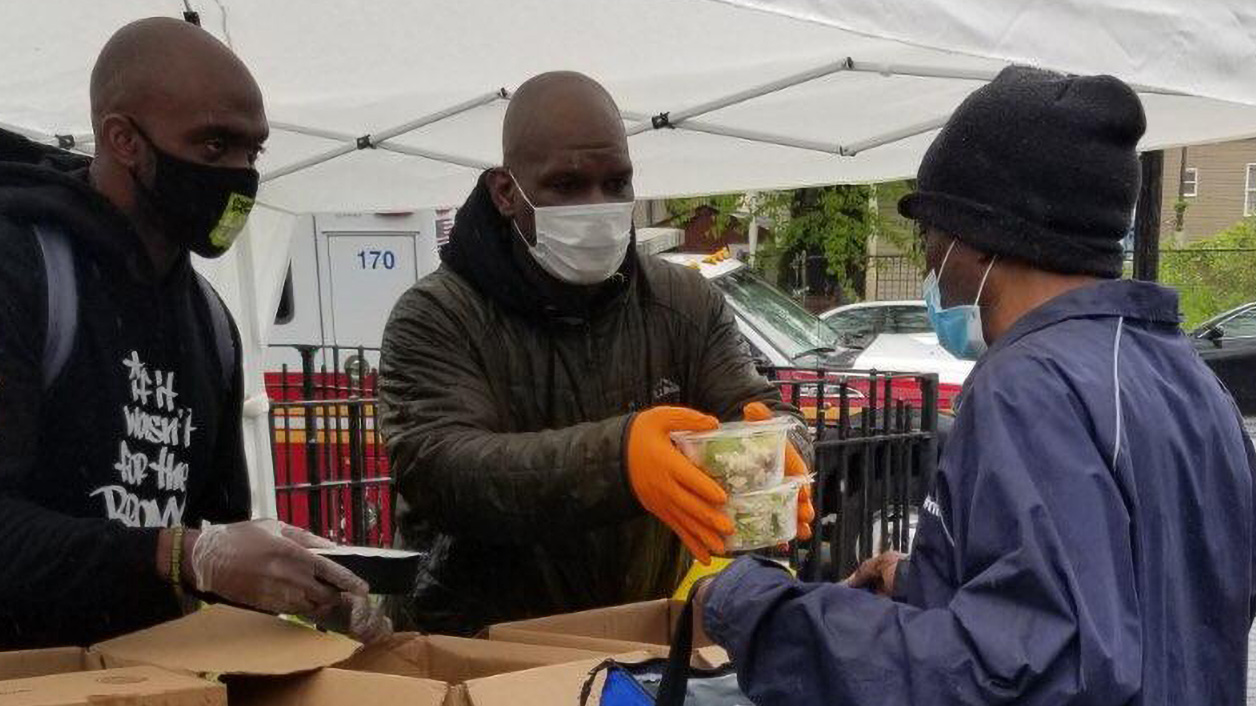 Men wearing protective masks distribute food.
