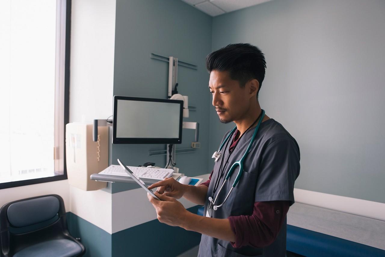 A male doctor reads a patient's chart.