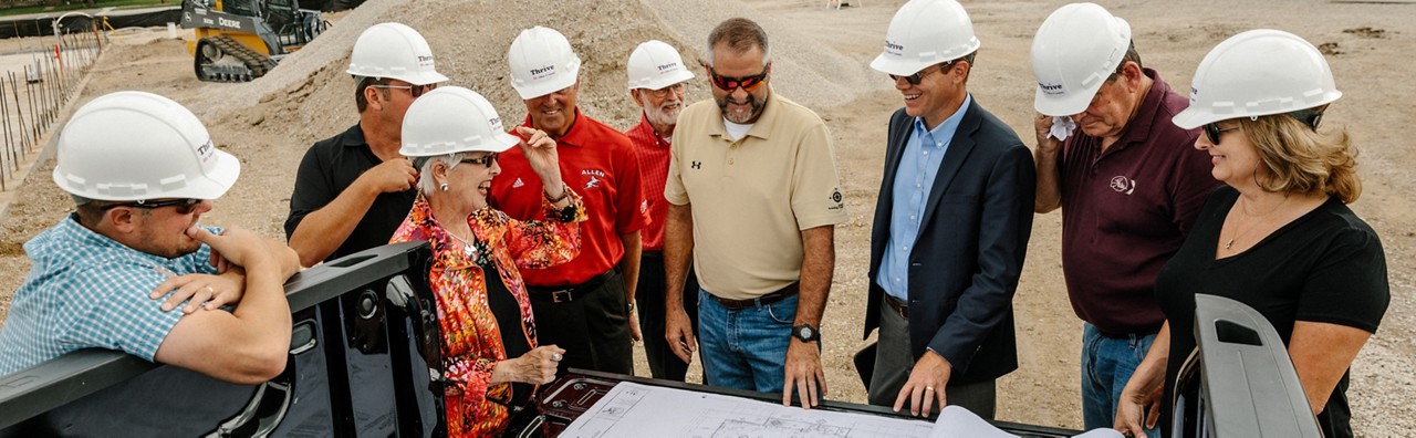 Construction staff and community officials discuss plans for a new grocery store. 