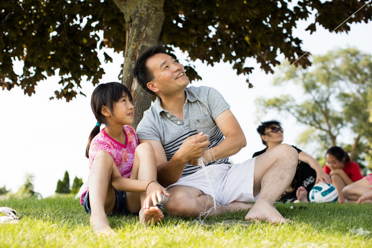 A father and daughter flying a kite in a park. A father and daughter flying a kite in a park.