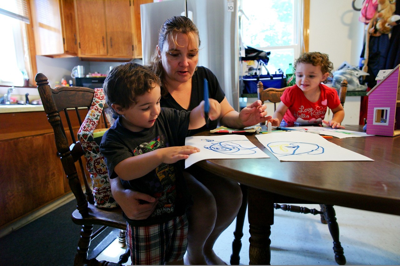 A mother and children enjoy drawing at the kitchen table. A mother and children enjoy drawing at the kitchen table.