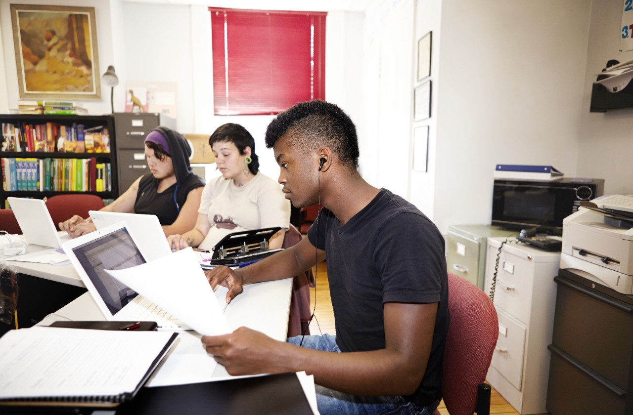 A group of young people working together in an office setting at a table.