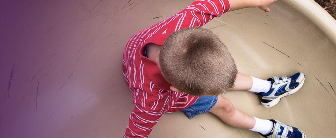 A young boy goes down a curved slide at a playground. A young boy goes down a curved slide at a playground.