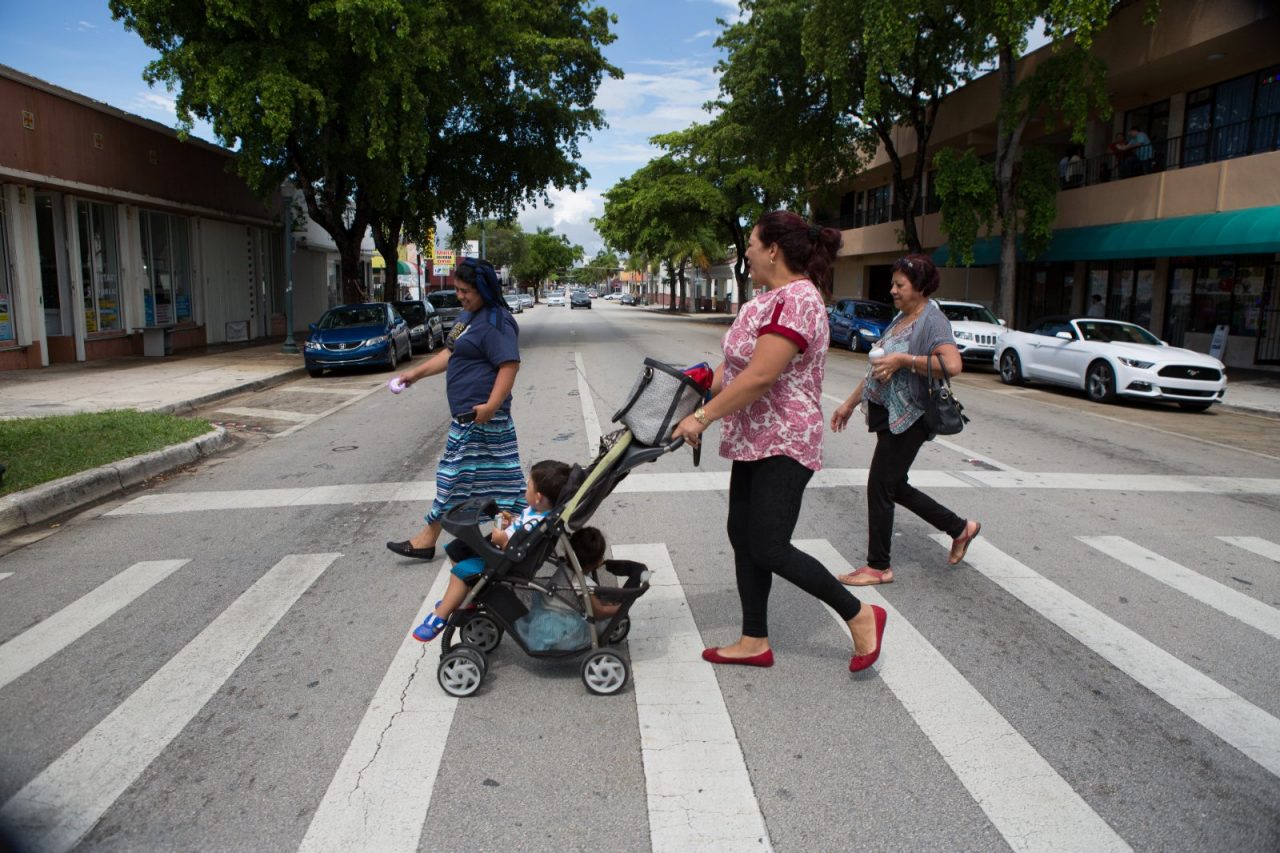 Women and a baby in a stroller crossing the street.