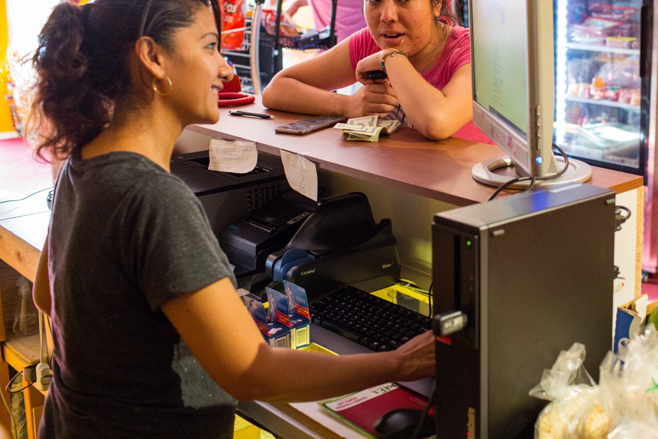 A woman smiles behind a counter at a store. 