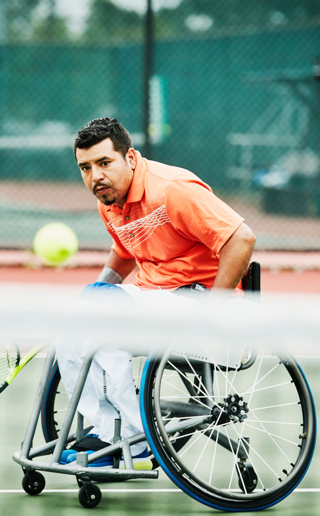 Adaptive athlete chasing down shot during wheelchair tennis match