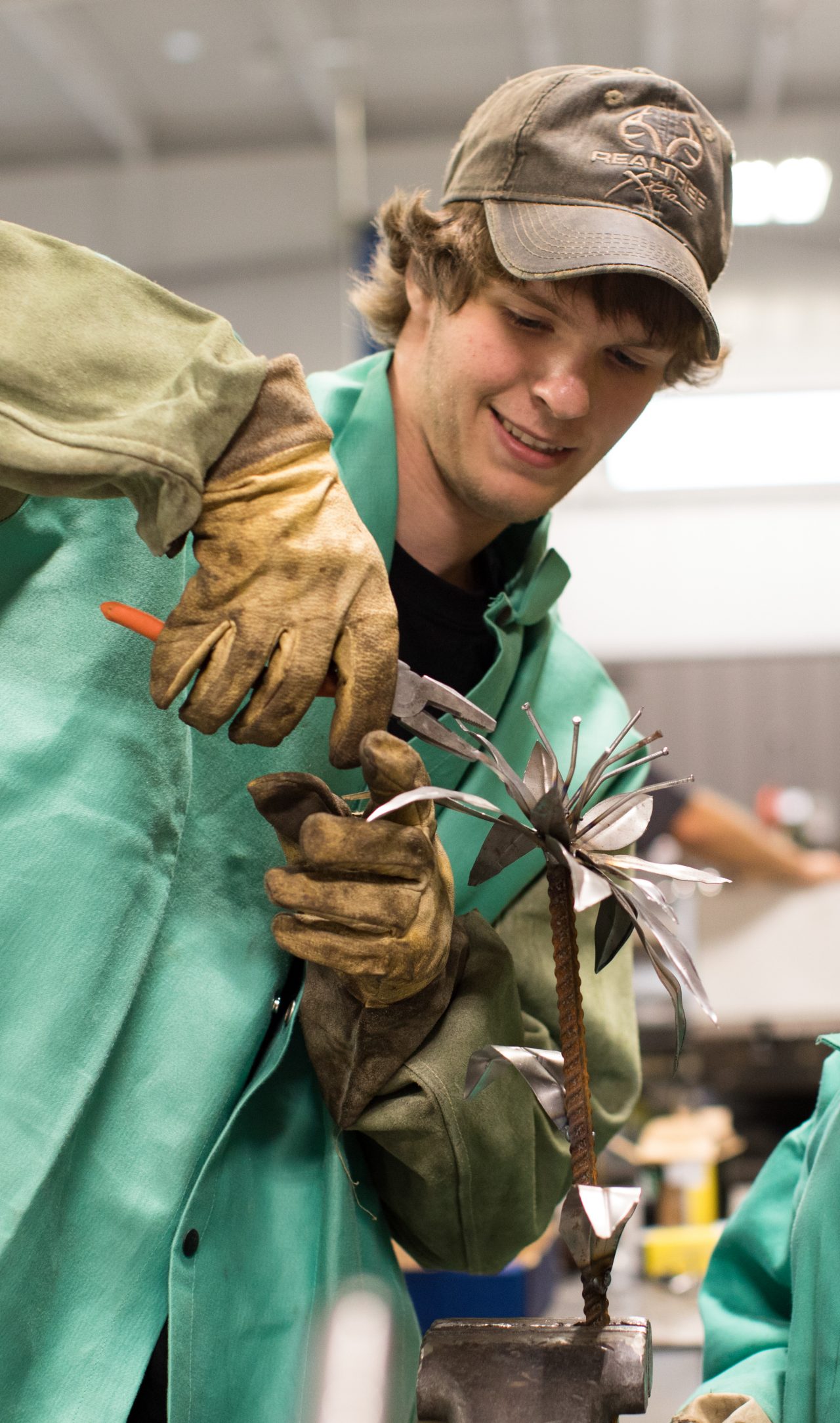 A teenager showing a fellow student how to use tools in metal class.