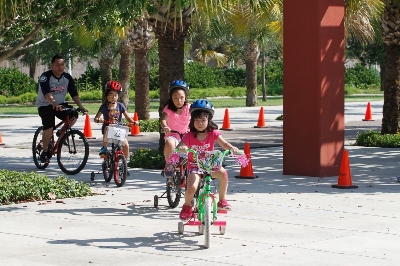 Parents and children riding bikes through a park.
