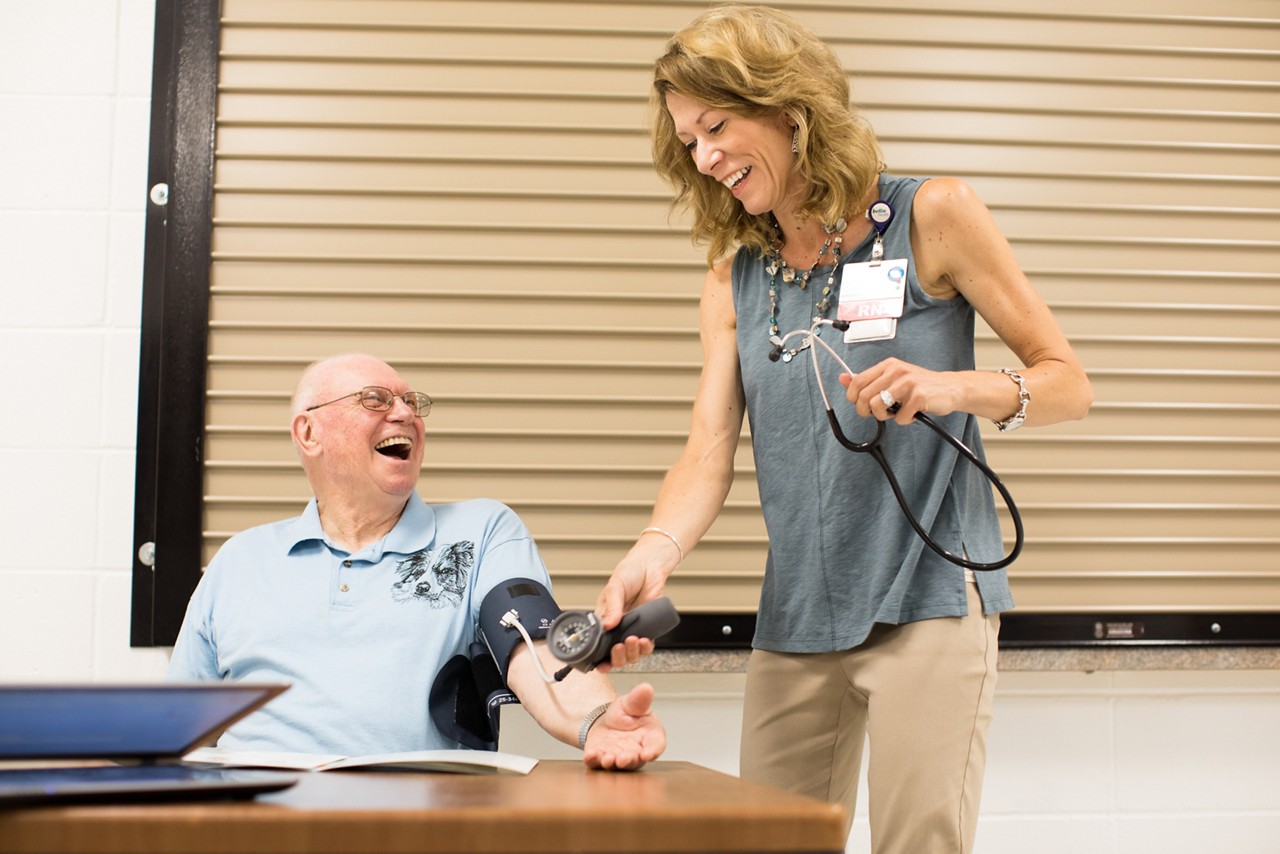 A nurse testing blood pressure at an outdoor health fair. A nurse testing blood pressure at an outdoor health fair.