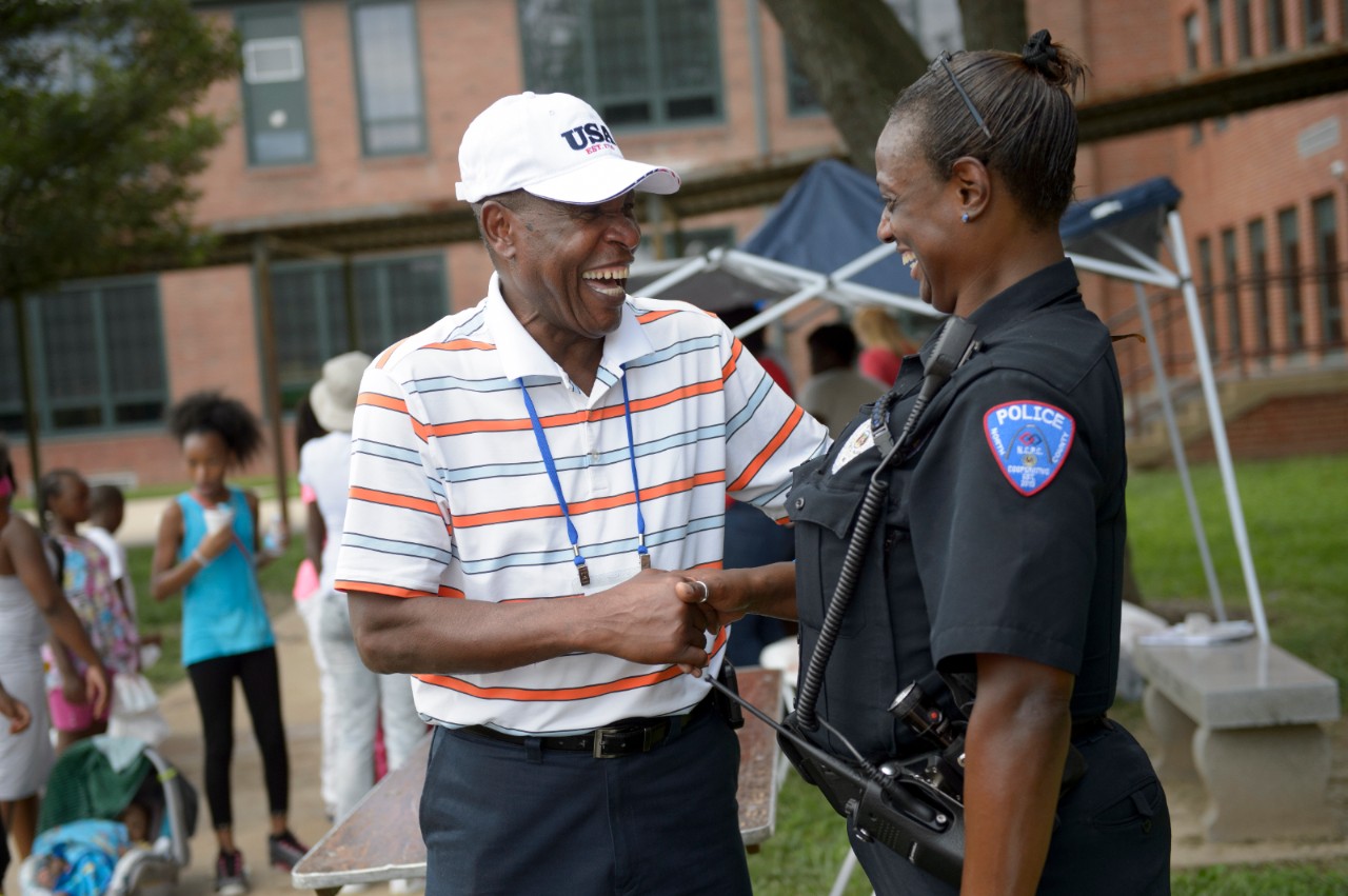 James McGee, mayor of Vinita Park, greets Officer Patricia Ash, with the North County Police Cooperative, during Beyond Housing's "Beyond the Backpack" event on Saturday, Aug. 6, 2016. The event, held at Normandy High School in Northern St. Louis County, Mo., provided families in the 24:1 communities with back-to-school resources, including immunizations and haircuts. (TRACIE VAN AUKEN/ For the Robert Wood Johnson Foundation)