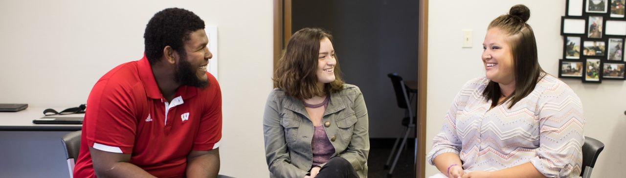 Three students talking in a classroom.