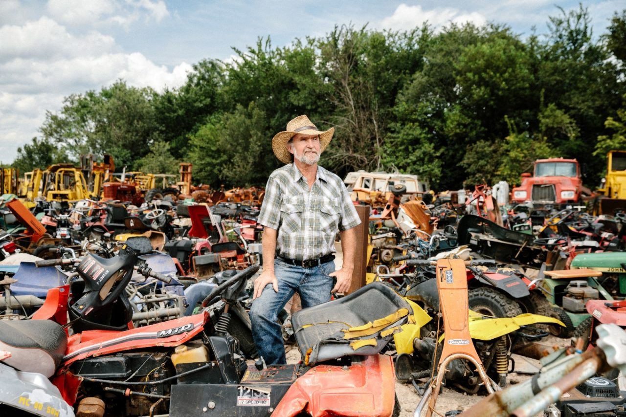 Ray Maloney standing near scrap material in his junkyard and auto salvage business.