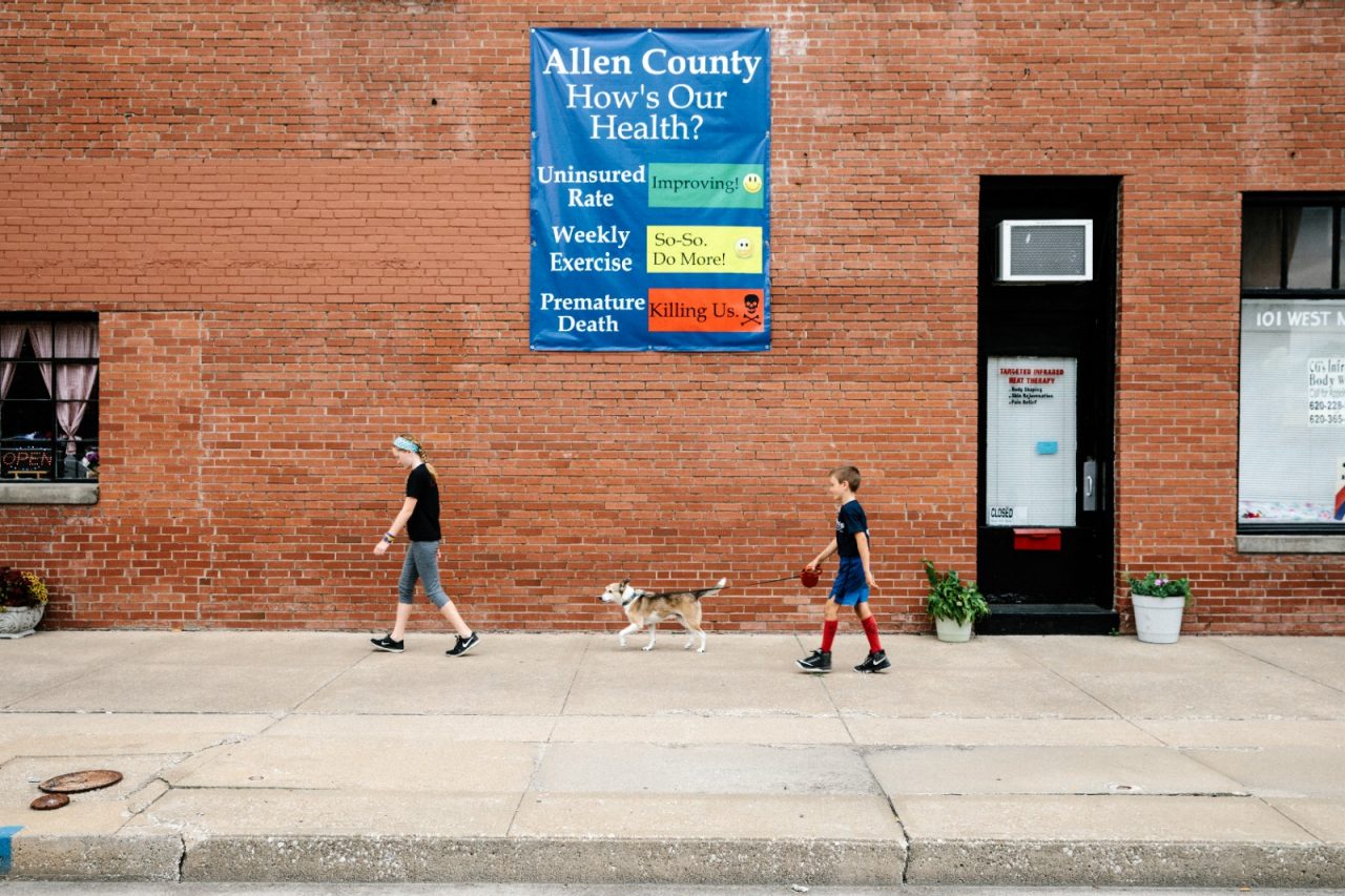 A poster asking "How's Our Health?" hangs on a building near the town square in downtown Iola, Kansas.