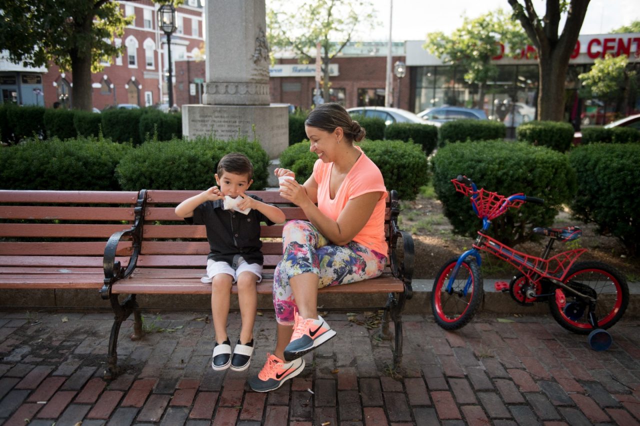 Milena Hernandez and her son David Hernandez, 3, eat Colombian ice cream treats in Chelsea Square. The square has been a focus of the Downtown Task Force, in hopes of making it a welcoming gathering place for Chelsea's citizens. (AEM Chelsea, MA story image) A new initiative called Chelsea Prospers aims to revitalize the city’s compact downtown and connect it to a Silver Line transit station set to open in Chelsea in 2018. As part of that effort, a downtown taskforce was launched in May. Composed of police, social services providers and public works staff and others, the group is working to reduce homelessness, drugs and loitering by connecting people with social services.
