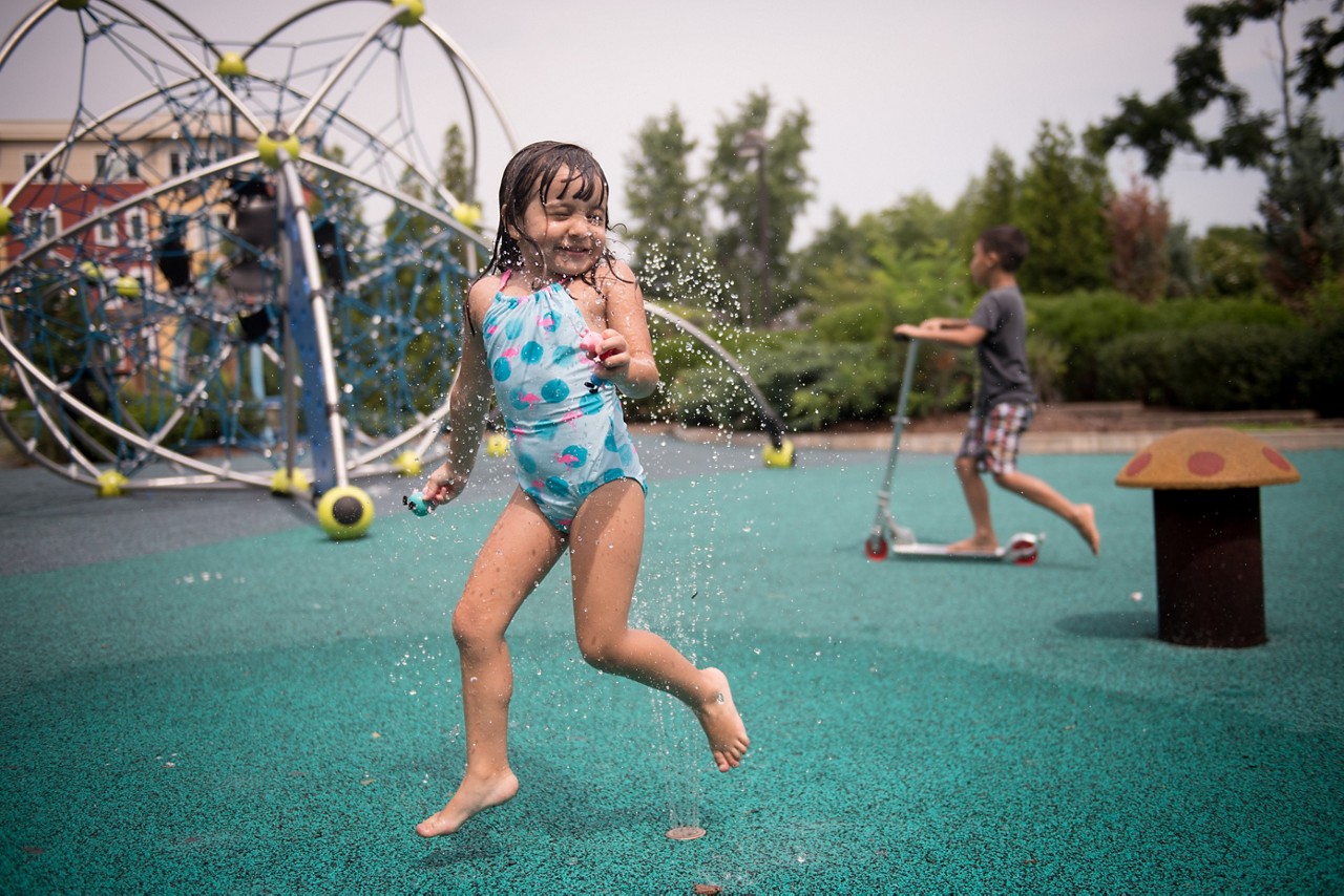 A young girl plays in a fountain.