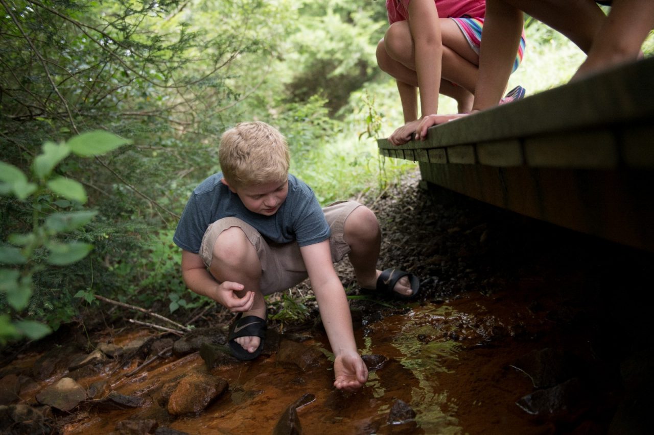 Drew Hordubay, 12, examines the water in the creek behind Crellin Elementary School. 