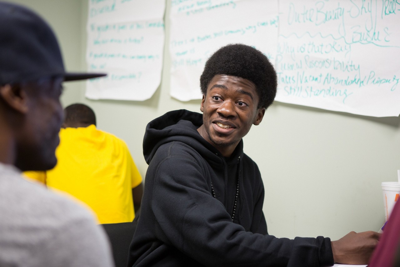 Two young adult students talking in a classroom.