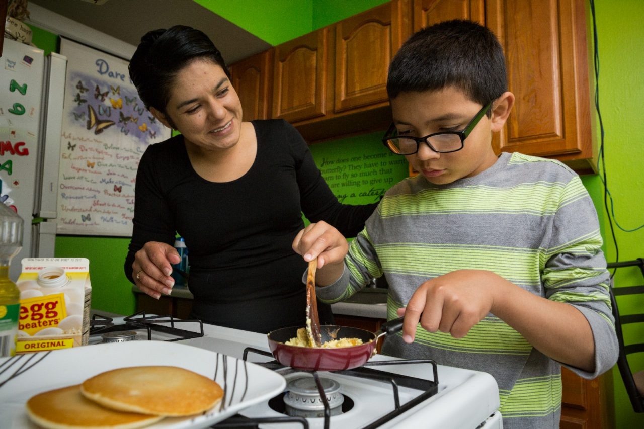 A mother teaching her son to cook.