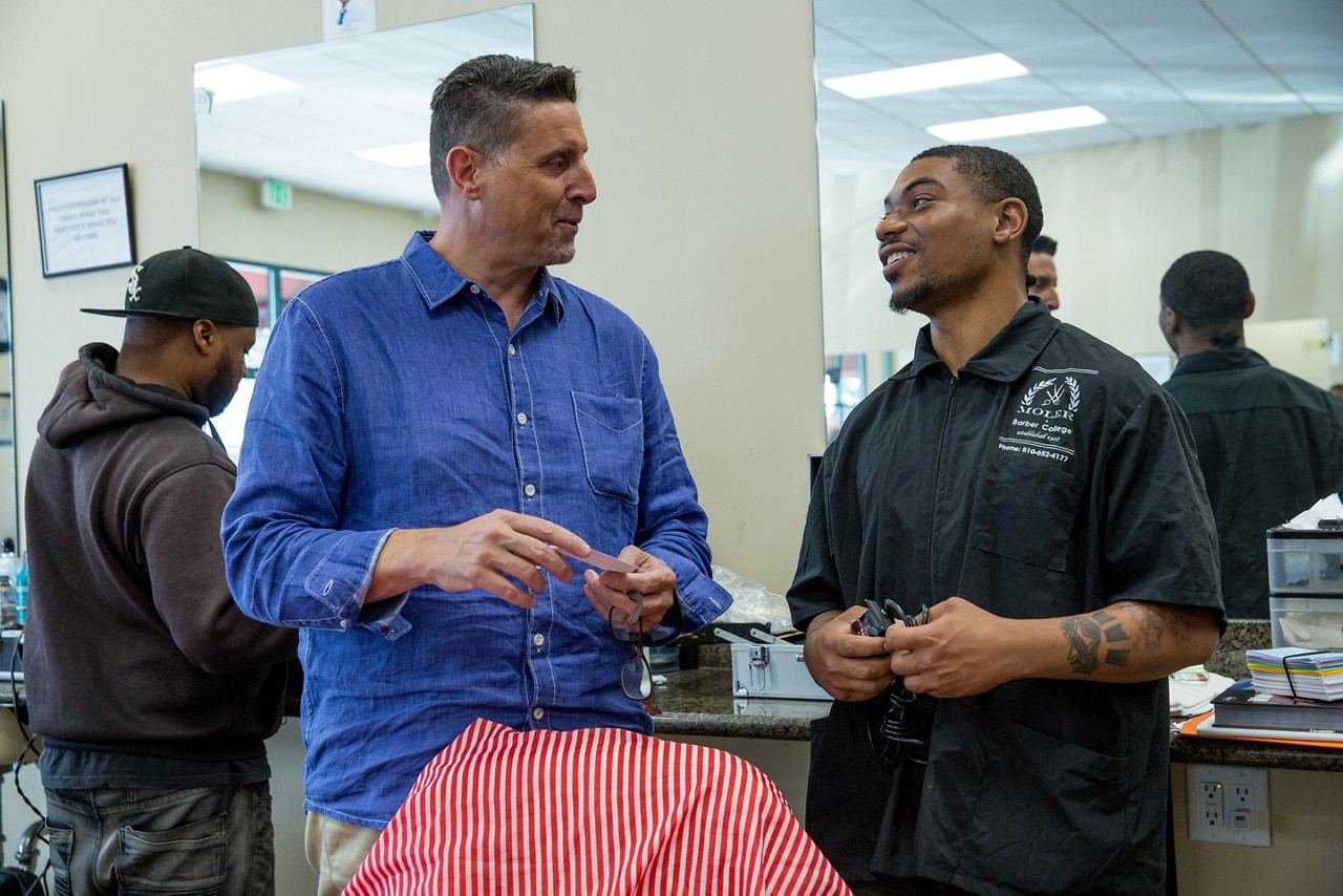 A barber teaches students the skills of the trade. 