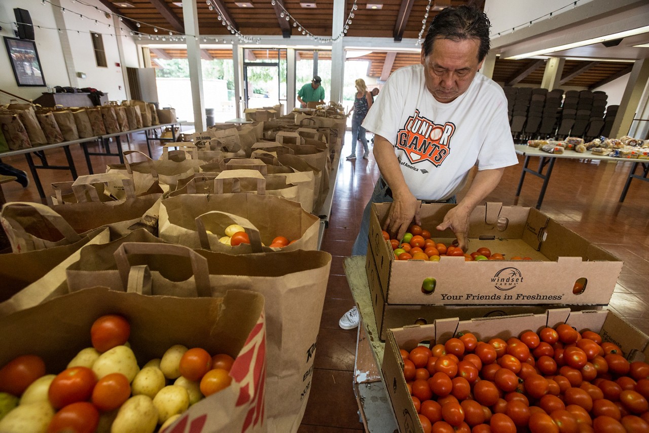 A volunteer preparing bags of food at a senior center.