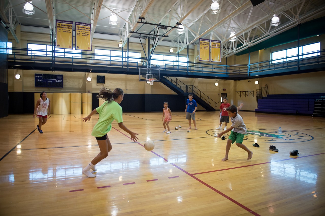 A family playing basketball on an inside court. 