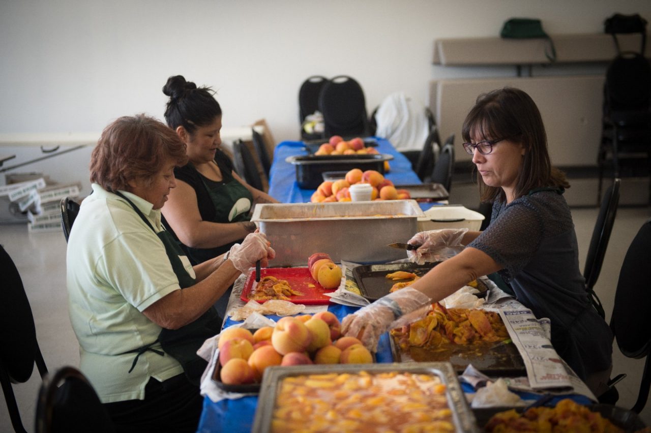 Women peeling peaches during a canning class. 